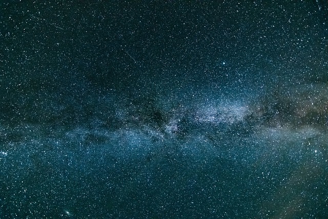 Panoramic view of the Milky Way galaxy with dense clusters of stars and dark interstellar dust bands, stretching across the night sky.