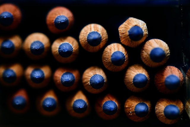 A close-up view of the tips of sharpened pencils arranged in a pattern, showcasing their pointed ends and wooden texture.