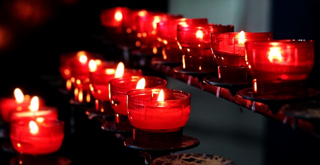 Row of glowing red candles symbolizing devotion, spirituality, and the enduring impact of world religions throughout history.