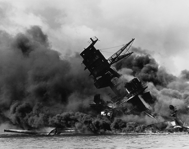 Black and white image of a battleship engulfed in smoke and flames during the attack on Pearl Harbor, symbolizing the devastation of the pivotal 1941 event.