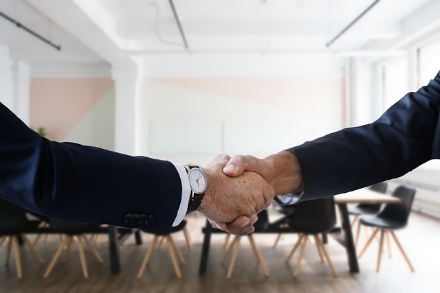 Two professionals shaking hands in a modern office setting, symbolizing successful salary negotiation and professional agreement